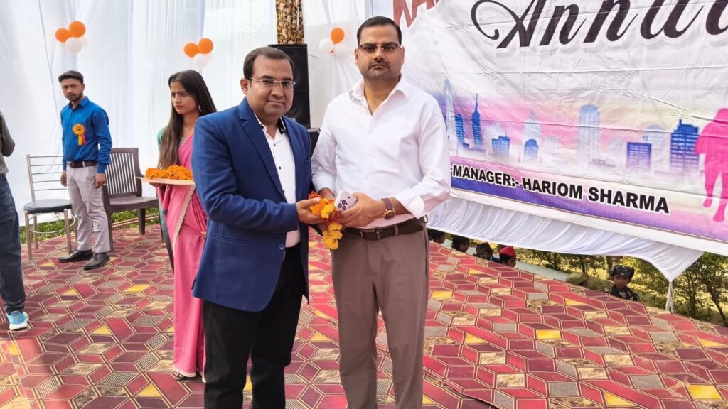 Principal Abhishek Srivastava garlanding a guest on the Annual Function stage, beneath the banner naming Manager Hariom Sharma.