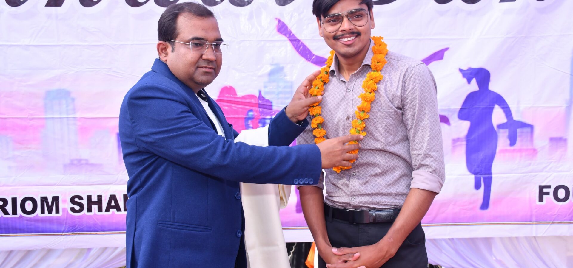 Principal Abhishek Srivastava placing a marigold garland around a young guest at the Annual Function.