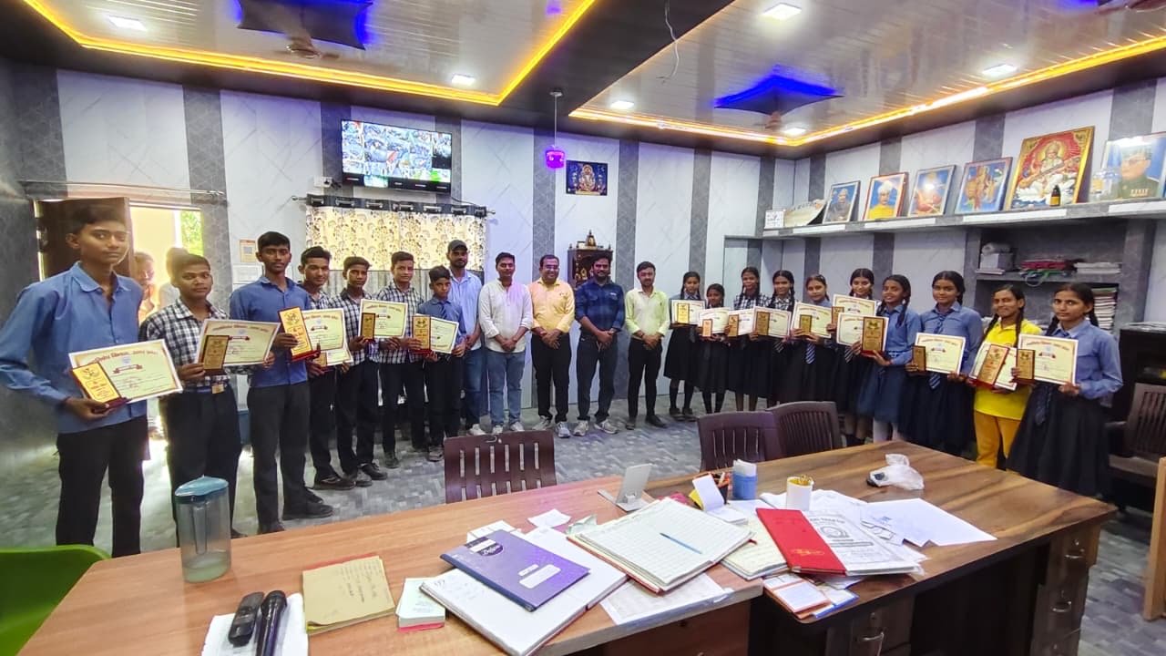 Row of students in uniform displaying merit certificates alongside their teachers in the college office