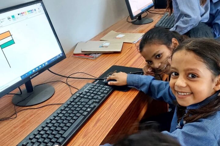 Primary students working at desktop computers in the computer lab at Karpoori Thakur Intermediate College