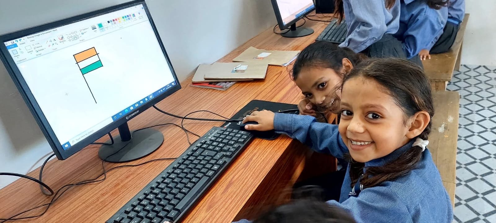 Primary students working at desktop computers in the computer lab at Karpoori Thakur Intermediate College