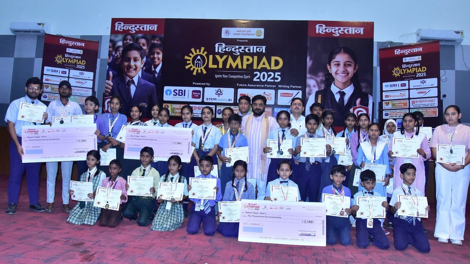 Students holding certificates and prize cheques at the Hindustan Olympiad 2025 award ceremony