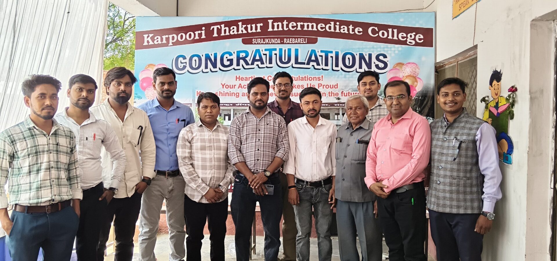 Teachers and staff of Karpoori Thakur Intermediate College standing beside a Congratulations banner for the students' results