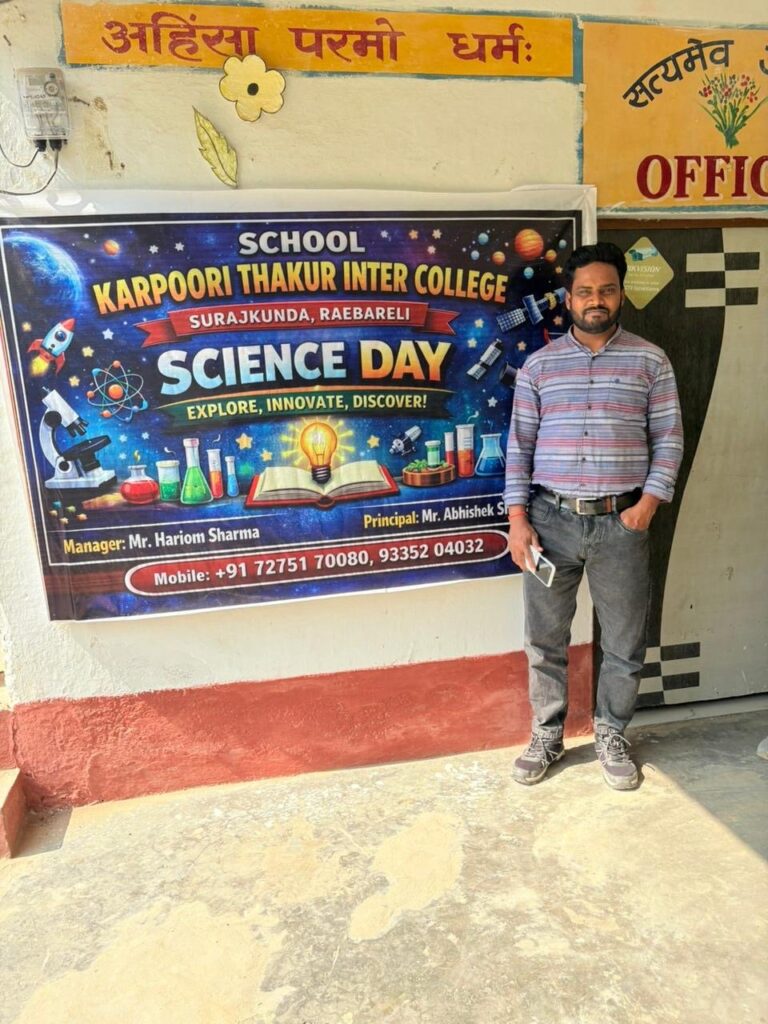 A staff member standing beside the Science Day banner reading Explore, Innovate, Discover outside the school office