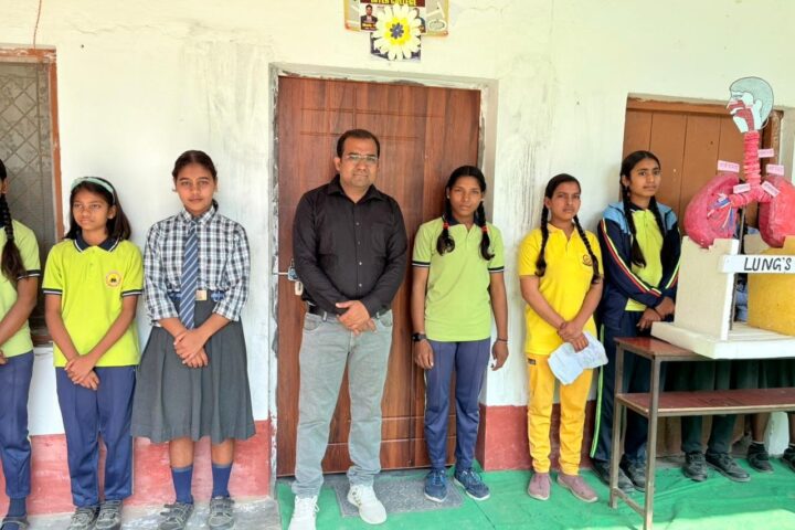 Students in school uniform standing with a teacher beside a hand-made model of the lungs on Science Day