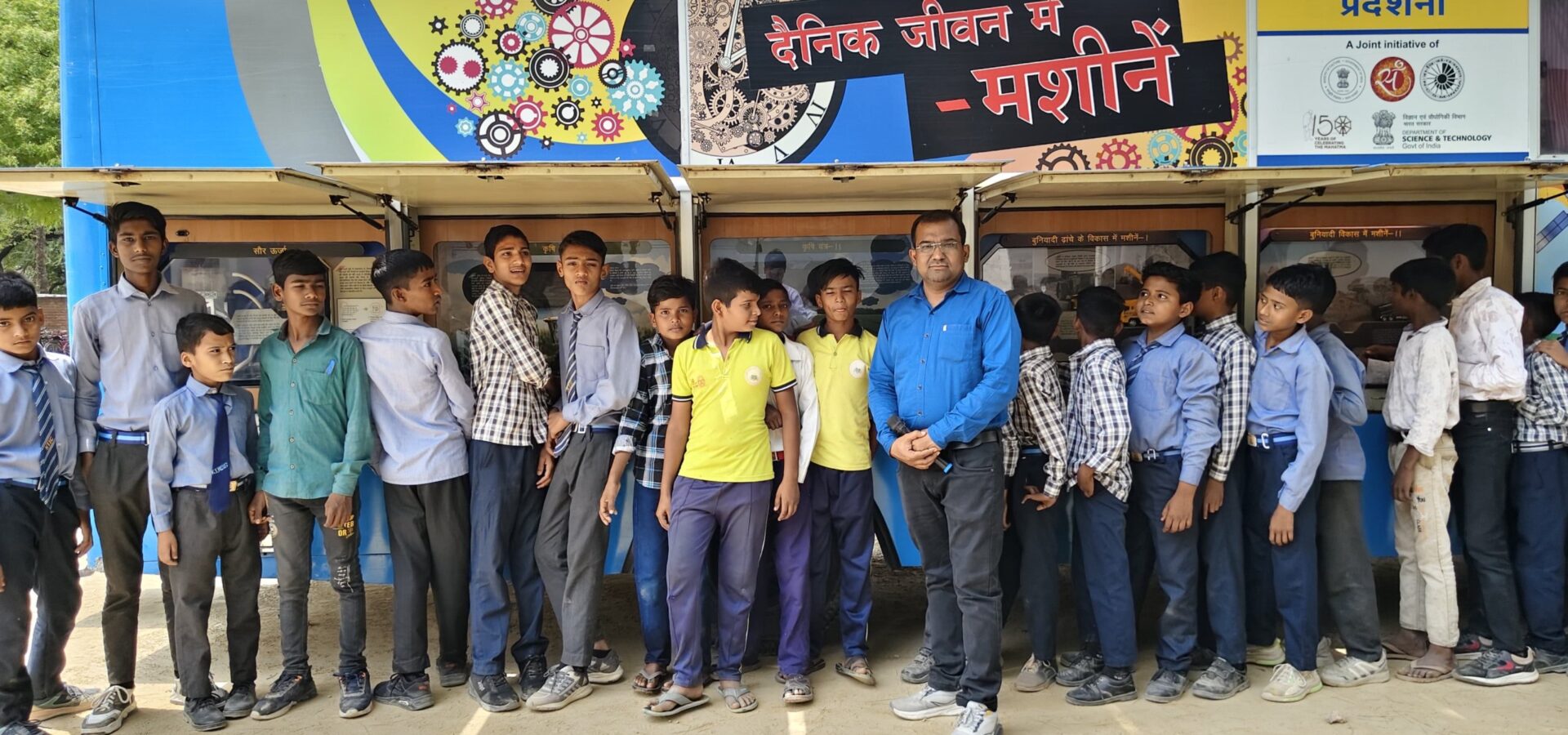 Students queuing along the open display panels of the Department of Science and Technology mobile science exhibition van on the theme Machines in Daily Life