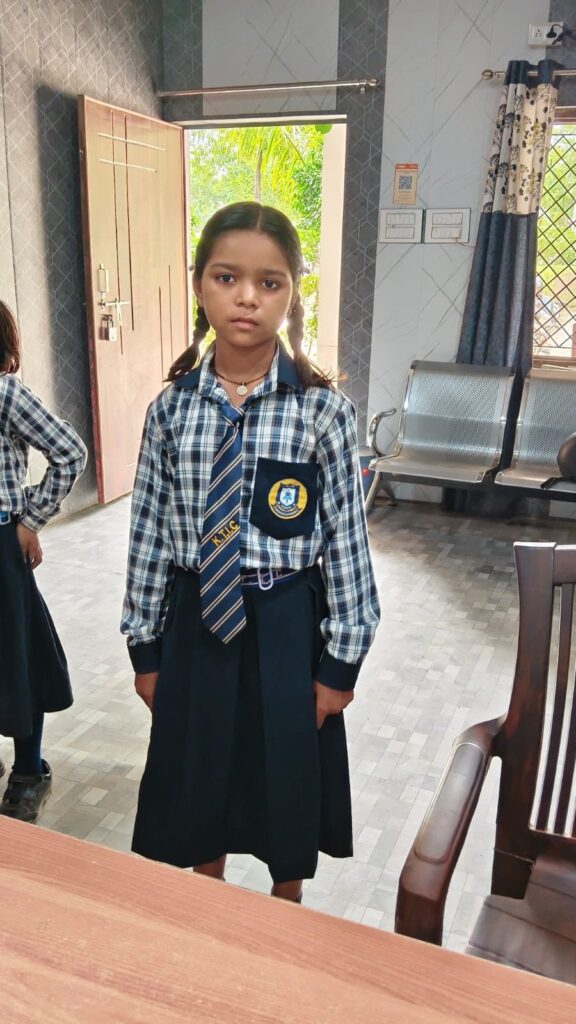 A student wearing the Karpoori Thakur Inter College uniform, tie and badge, standing in the college office.