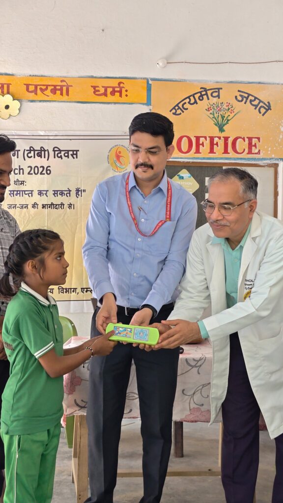 A student in a green tracksuit receiving a nutrition kit from a health department official and a doctor in a white coat at the college's World TB Day programme, March 2026.